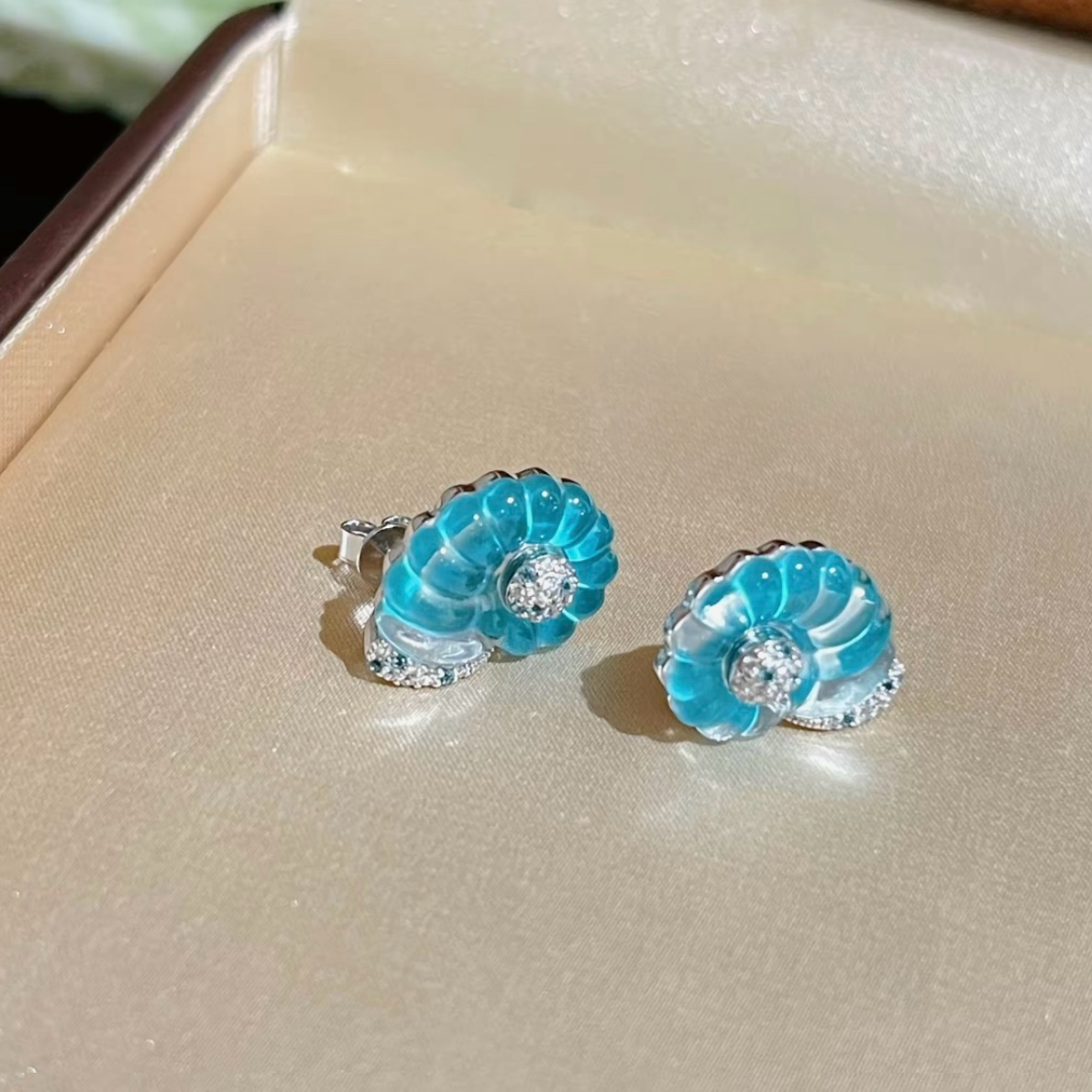 Rhodium-plated sterling silver nautilus shell stud earrings with blue cubic zirconia and clear pavé accents