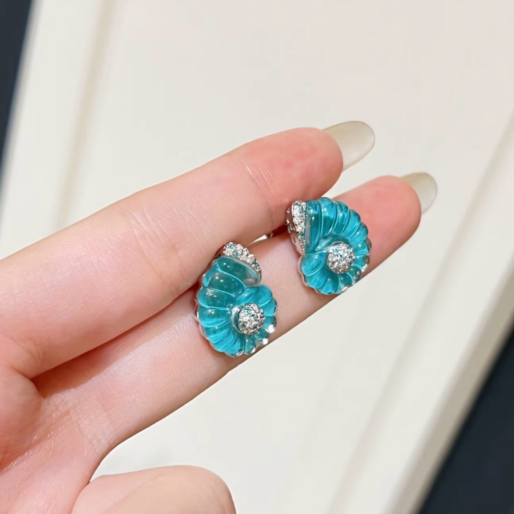 Rhodium-plated sterling silver nautilus shell stud earrings with blue cubic zirconia and clear pavé accents