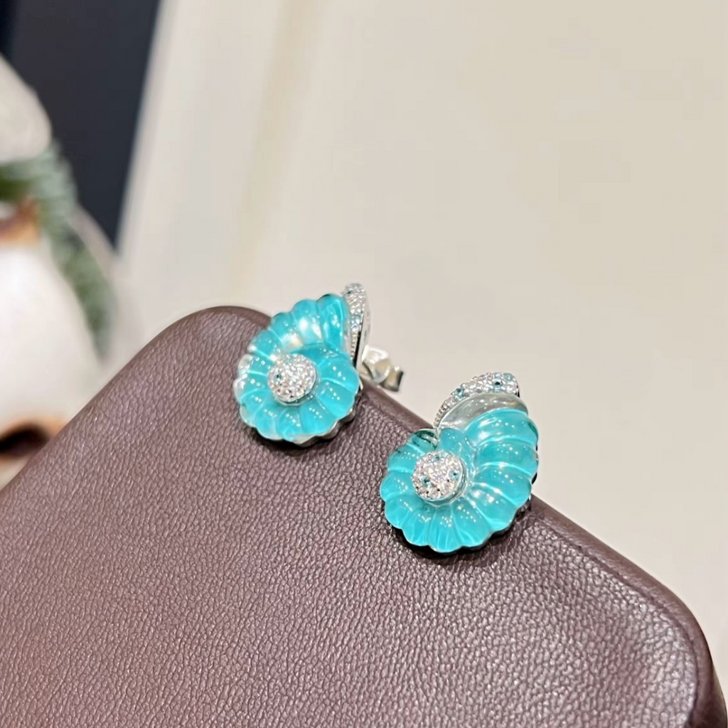 Rhodium-plated sterling silver nautilus shell stud earrings with blue cubic zirconia and clear pavé accents