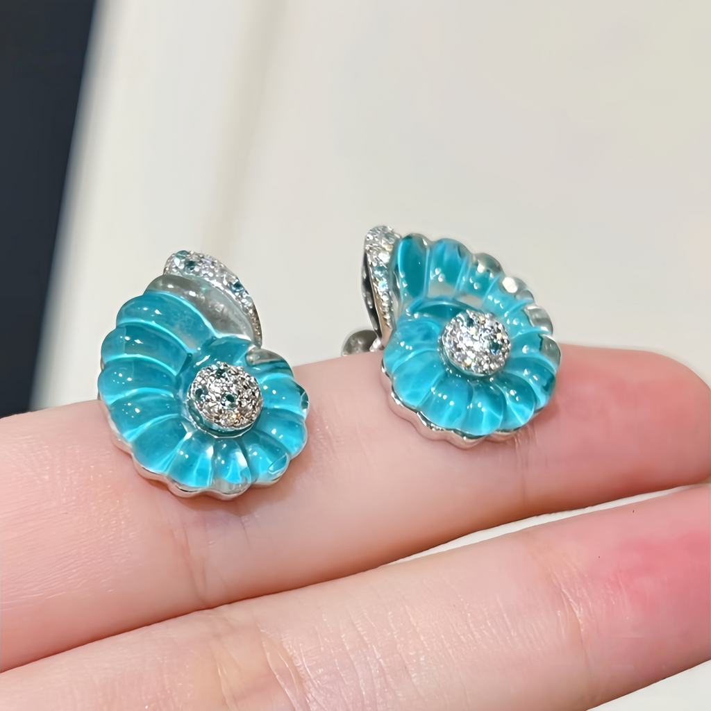 Rhodium-plated sterling silver nautilus shell stud earrings with blue cubic zirconia and clear pavé accents