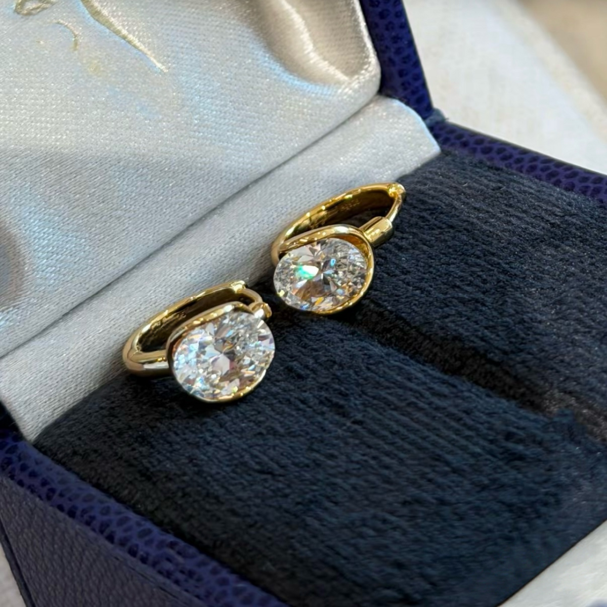 Gold and silver sterling silver huggie earrings with a suspended clear cushion-cut cubic zirconia stone