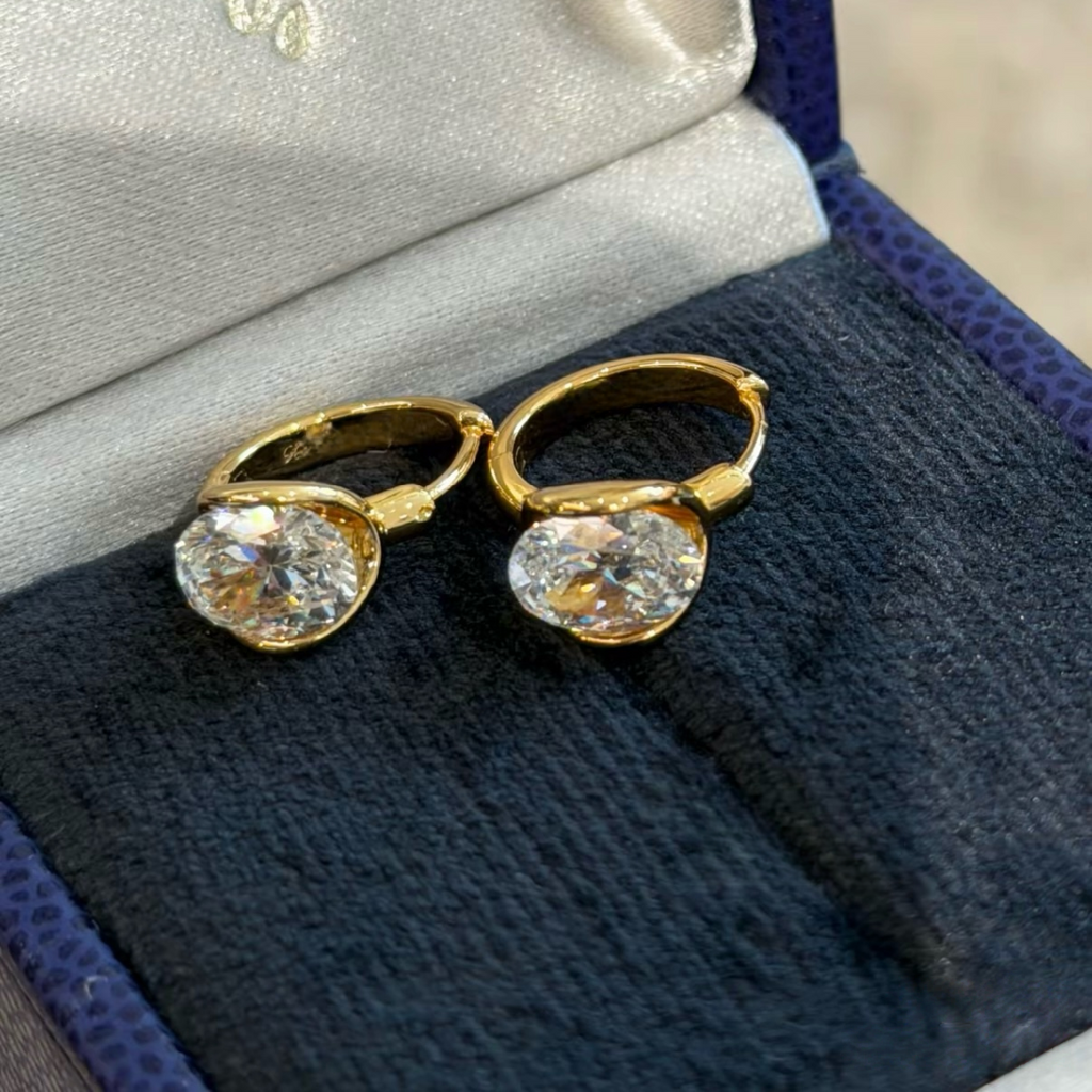 Gold and silver sterling silver huggie earrings with a suspended clear cushion-cut cubic zirconia stone
