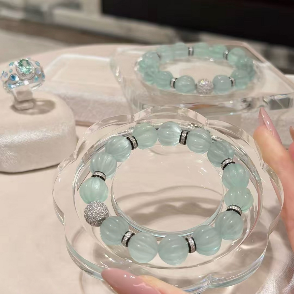 Pale mint-blue natural fluorite bracelet with carved pumpkin beads, transparent spacer elements, sterling silver decorative rings, and sparkling accent bead