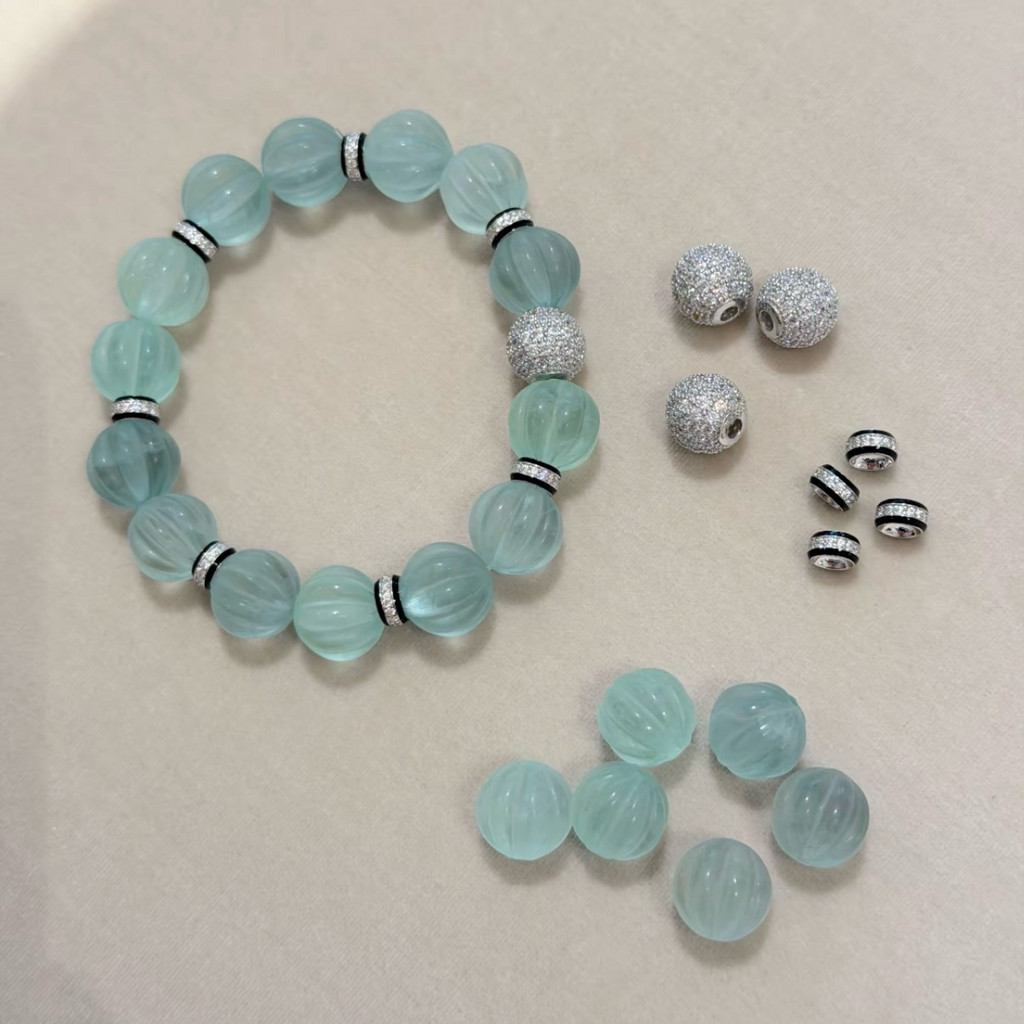 Pale mint-blue natural fluorite bracelet with carved pumpkin beads, transparent spacer elements, sterling silver decorative rings, and sparkling accent bead