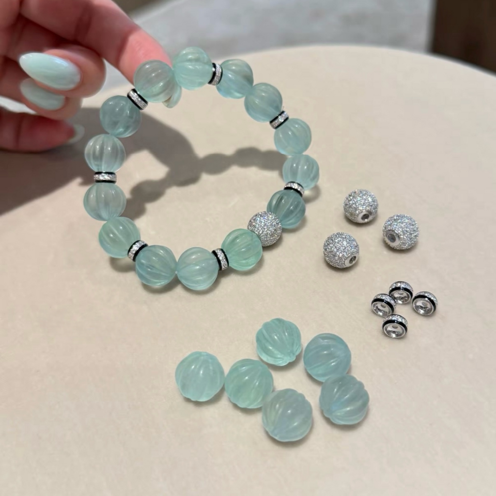 Pale mint-blue natural fluorite bracelet with carved pumpkin beads, transparent spacer elements, sterling silver decorative rings, and sparkling accent bead