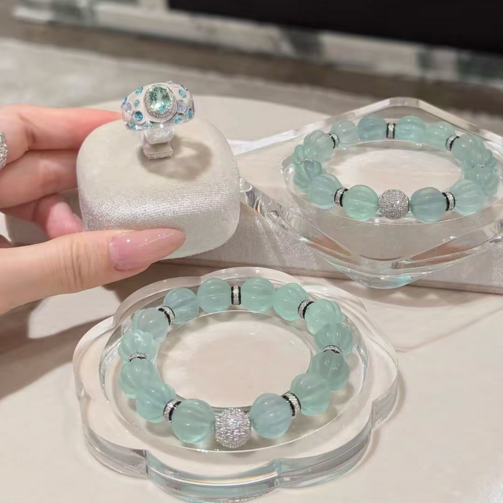 Pale mint-blue natural fluorite bracelet with carved pumpkin beads, transparent spacer elements, sterling silver decorative rings, and sparkling accent bead