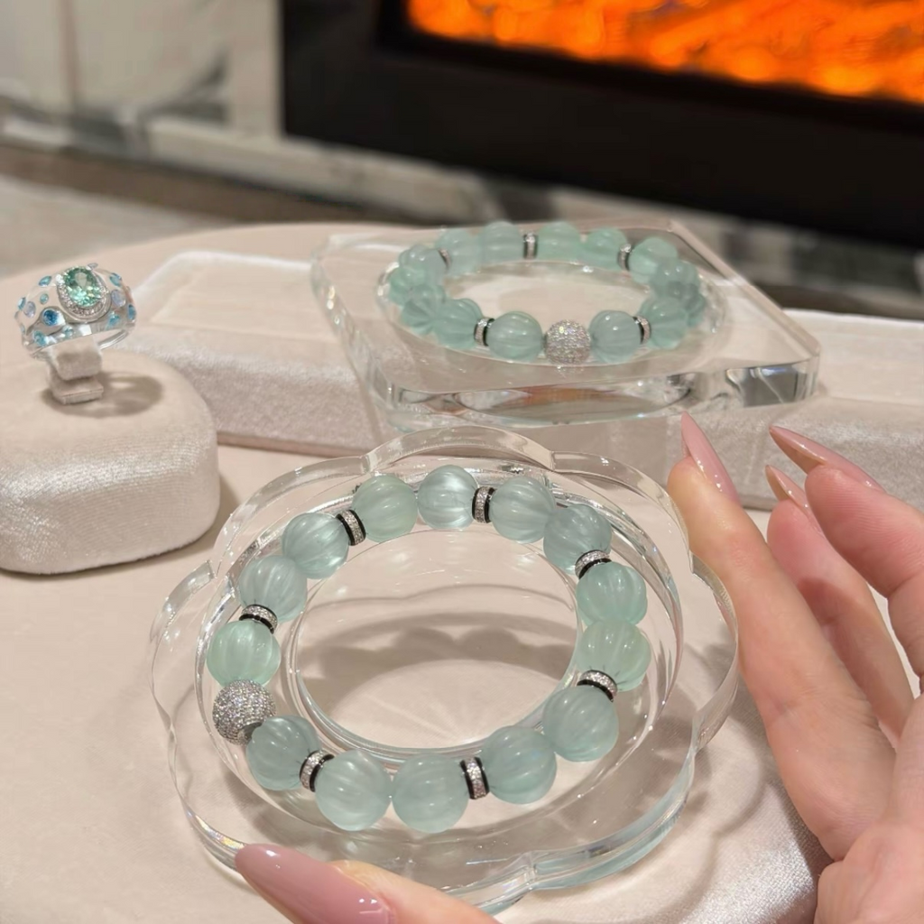 Pale mint-blue natural fluorite bracelet with carved pumpkin beads, transparent spacer elements, sterling silver decorative rings, and sparkling accent bead